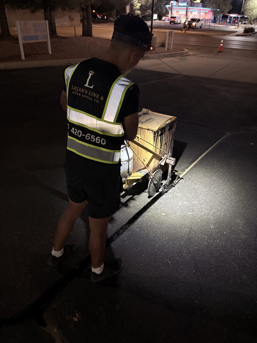 Lujan's Line crew in branded reflective vest performing crack filling at night