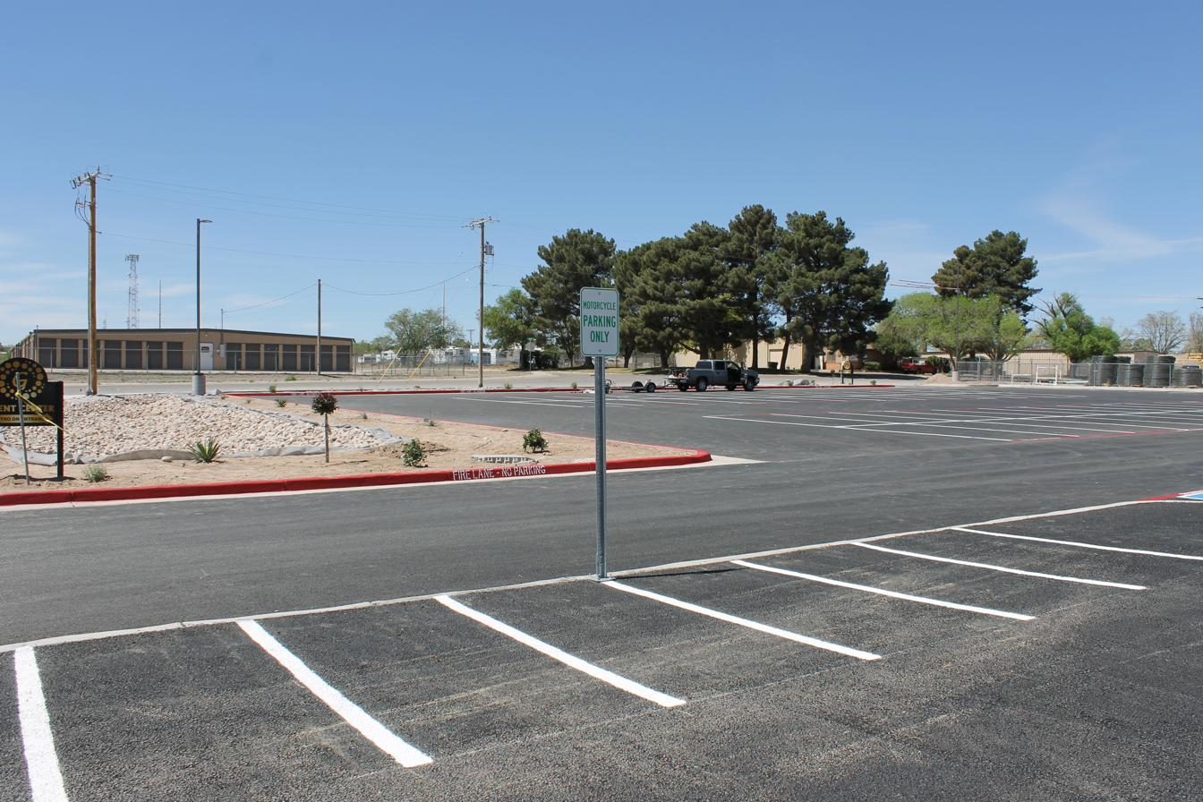 Wide view of motorcycle parking layout with new signage and lot in background